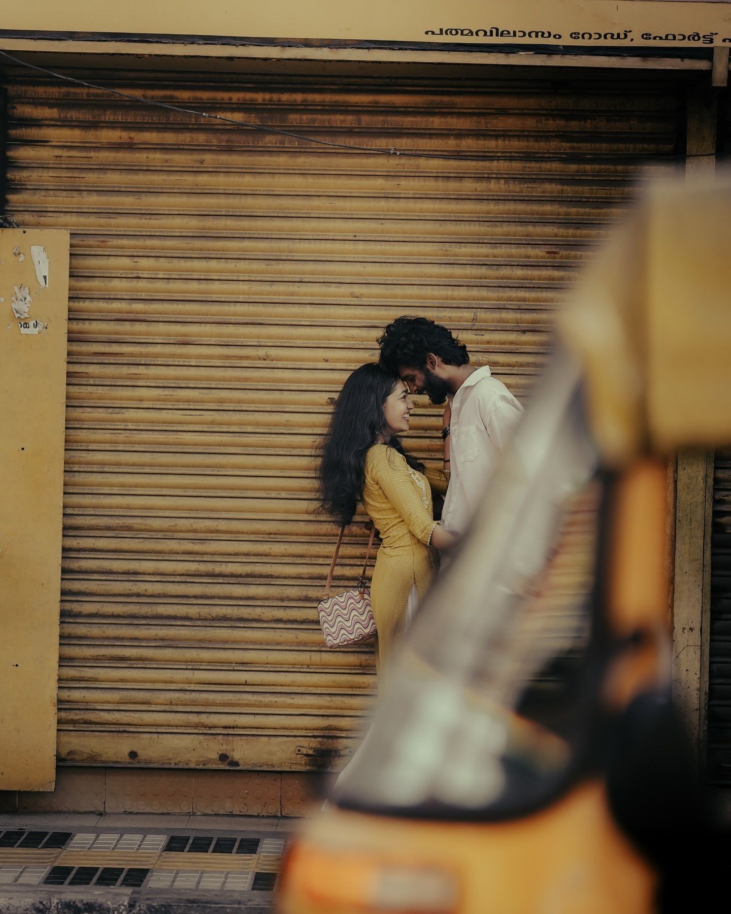 Couple standing in front of a closed shop with yellow shutters. Image from Cosmos. 