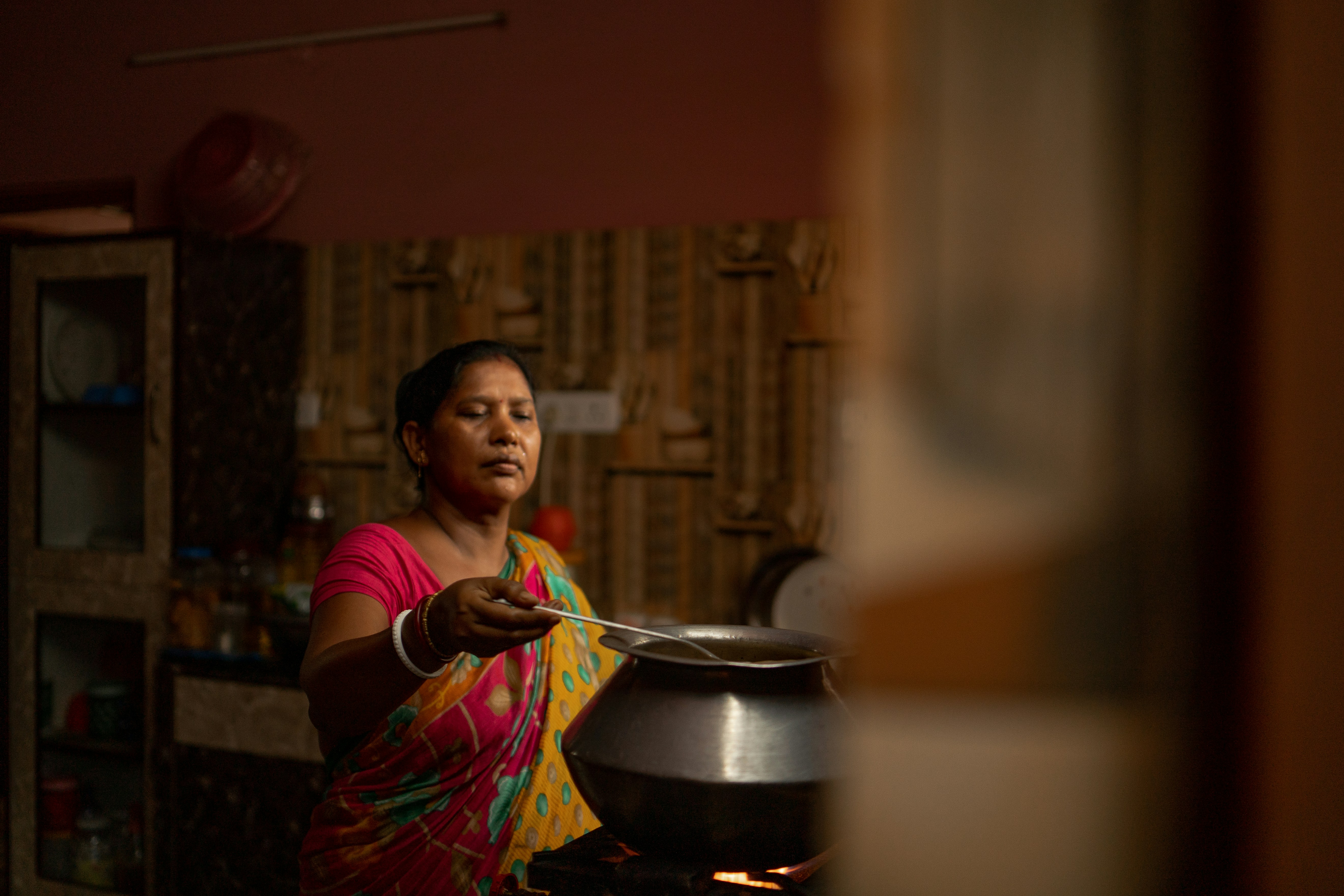 Indian woman wearing saree, cooking on the gas. Photo by Shelby Murphy Figueroa